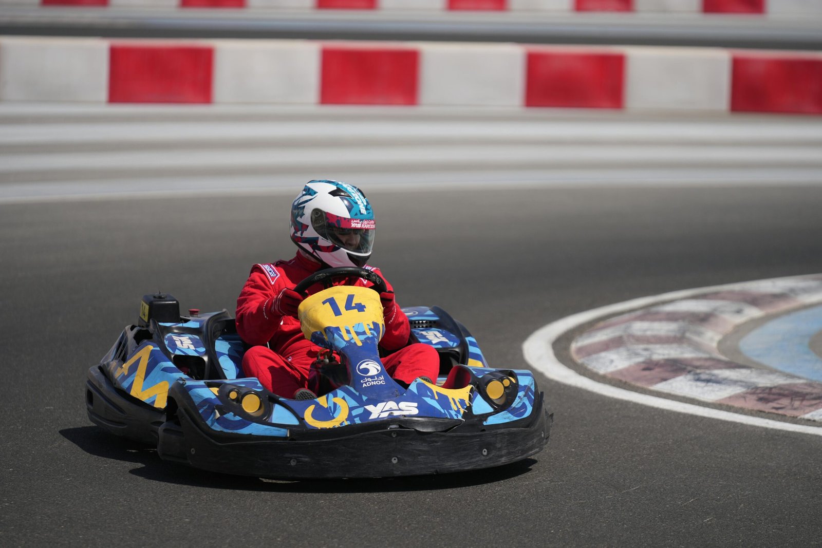 A go-kart racer in red suit speeds on Yas Marina Circuit in Abu Dhabi.